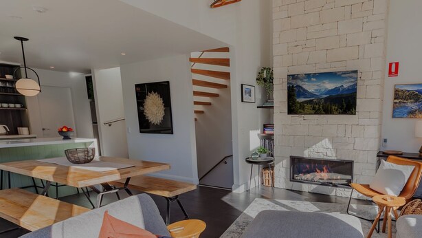 Een moderne woonkamer met een open haard, een eethoek en een keuken op de achtergrond.