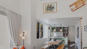 Een moderne woonkamer met een bank, een eettafel en een keuken op de achtergrond.