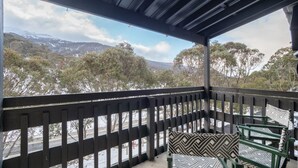 A covered outdoor seating area with a view of a snowy landscape and mountains.