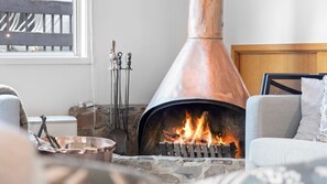 Un salon chaleureux avec une cheminée en pierre, un canapé confortable et un banc en bois.