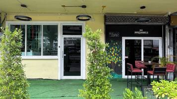 A restaurant with outdoor seating, a green artificial turf, and potted plants.