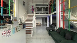 A hotel lobby with a reception desk, a staircase, and a green sofa. - Lemon Tree Khaosan Hostel (Bangkok)