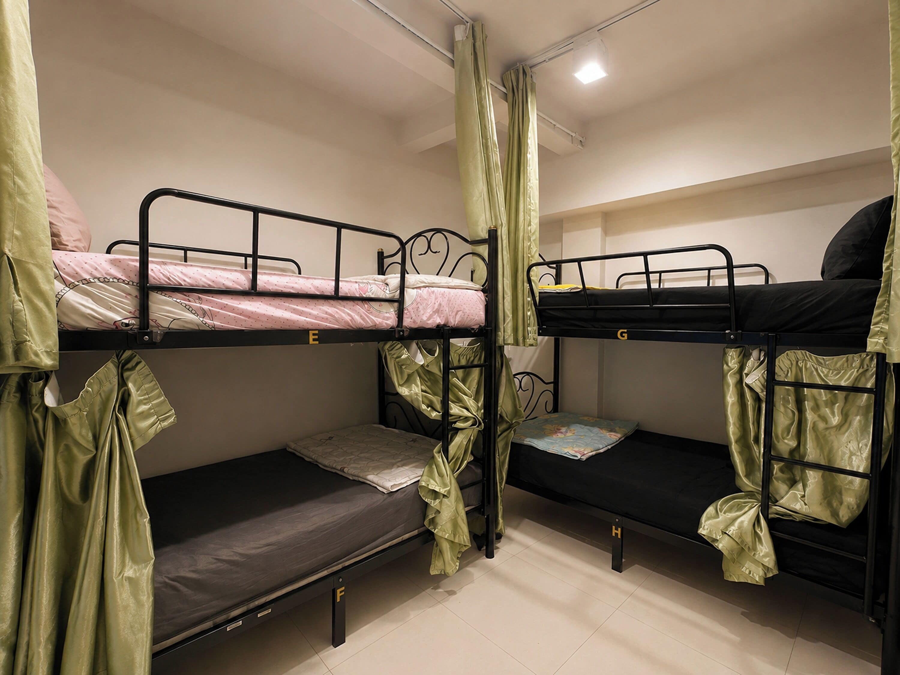 A dormitory room with bunk beds, a curtain, and a small table.