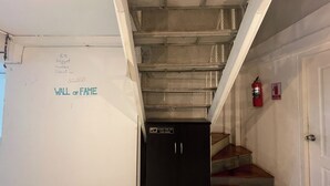 A staircase with metal railings, a fire extinguisher, and a sign on the wall. - Lemon Tree Khaosan Hostel (Bangkok)