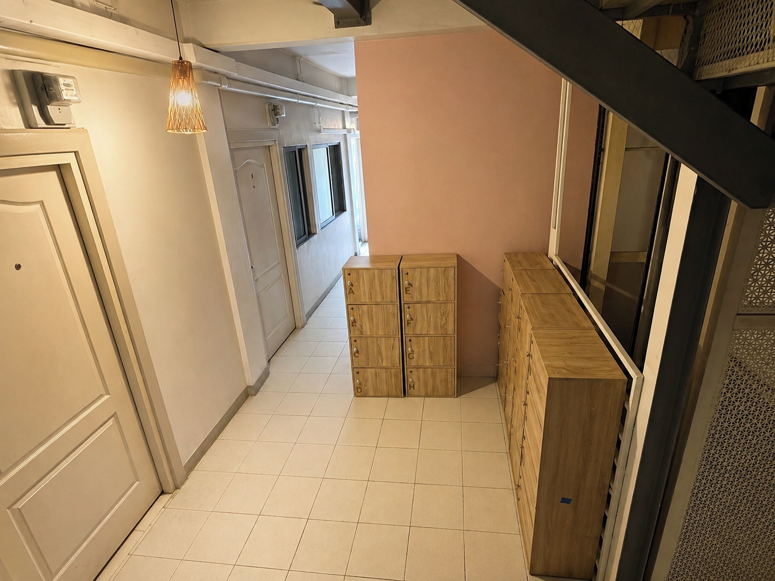 A hallway with a wooden cabinet, a door, and a hanging light fixture.