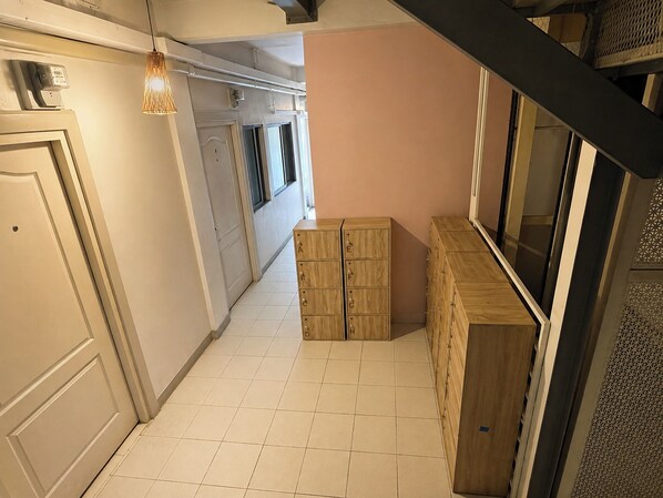 A hallway with a wooden cabinet, a door, and a hanging light fixture. - Lemon Tree Khaosan Hostel (Bangkok)