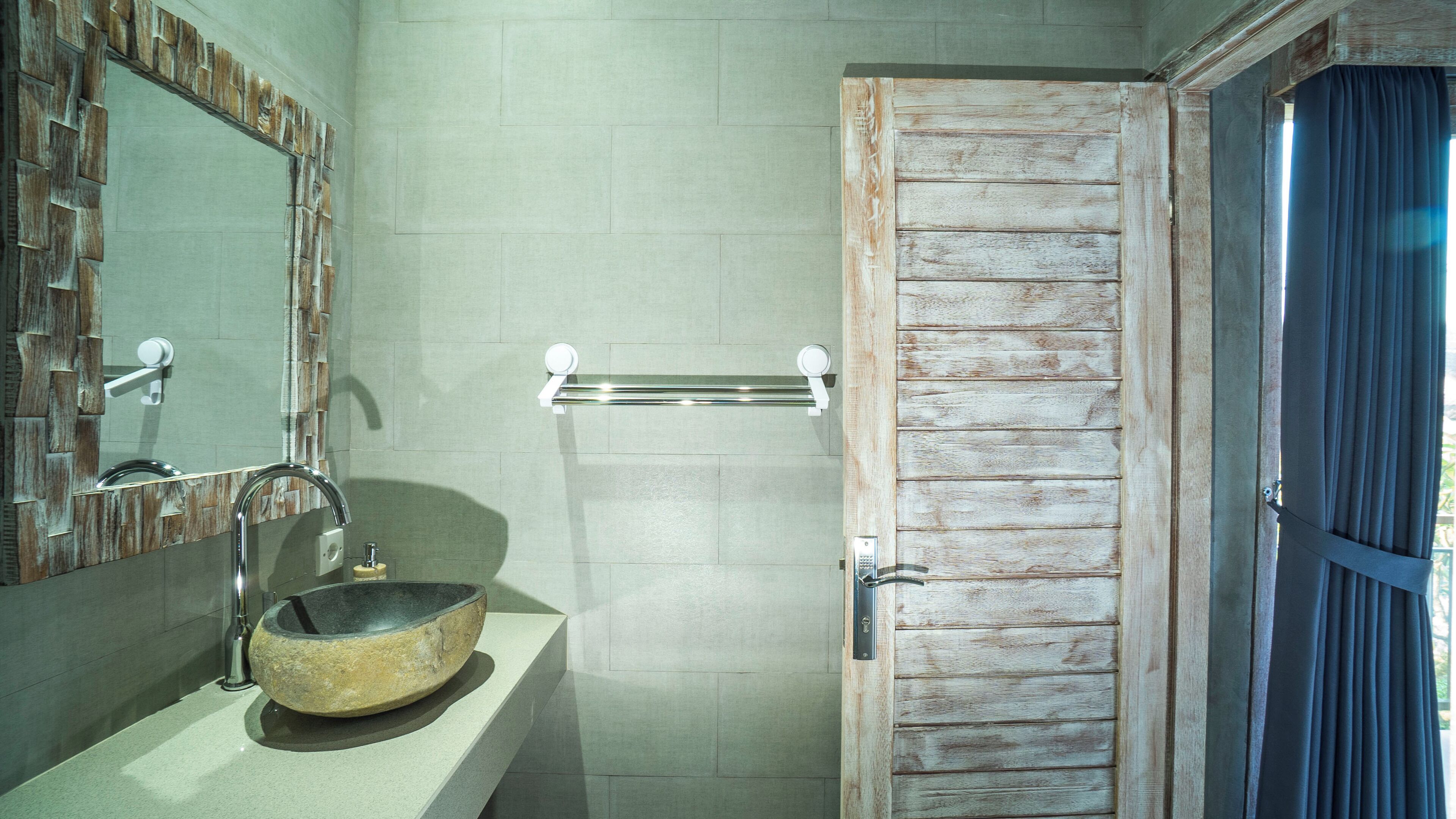 Une salle de bain avec un lavabo en pierre, une porte en bois et un miroir encadré de pierre.
