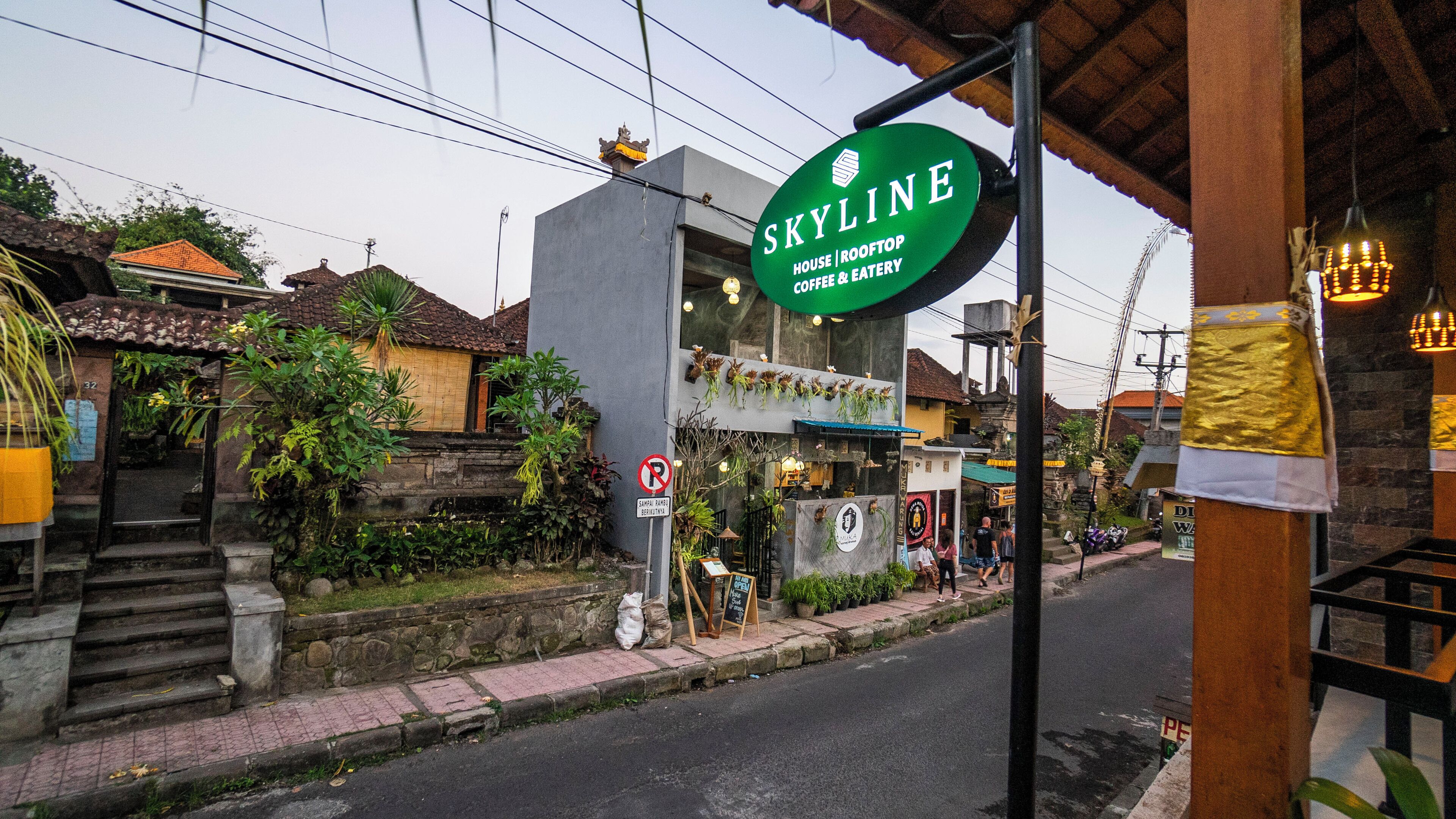 A street view with a green sign for 'Skyline House | Rooftop Coffee & Eatery'.