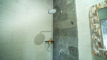 A shower with a handheld showerhead, a wall-mounted faucet, and a soap dispenser.
