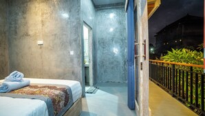 A modern hotel room with a large bed, a bathroom visible through an open door, and a balcony with plants. - Skyline House Ubud View by EPS (Ubud)