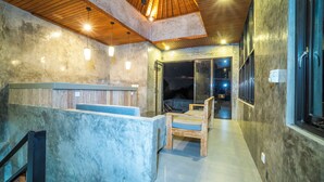 A modern interior with a reception desk, seating area, and a glass door leading outside. - Skyline House Ubud View by EPS (Ubud)