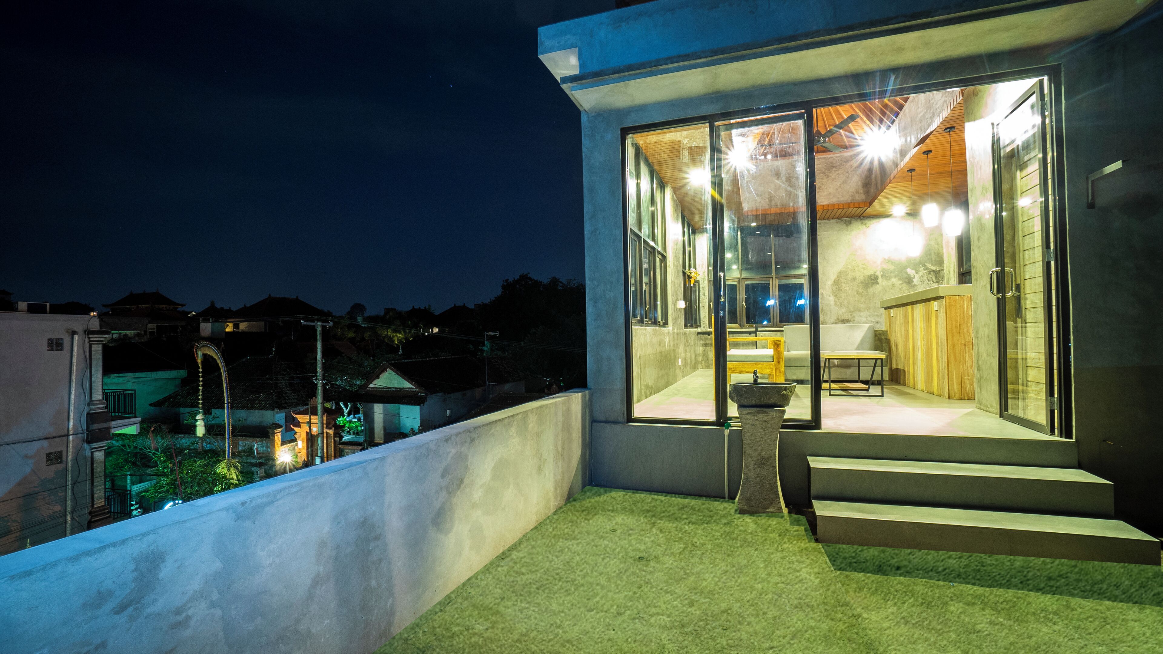 A modern building with large glass windows, a small outdoor seating area, and a concrete exterior.