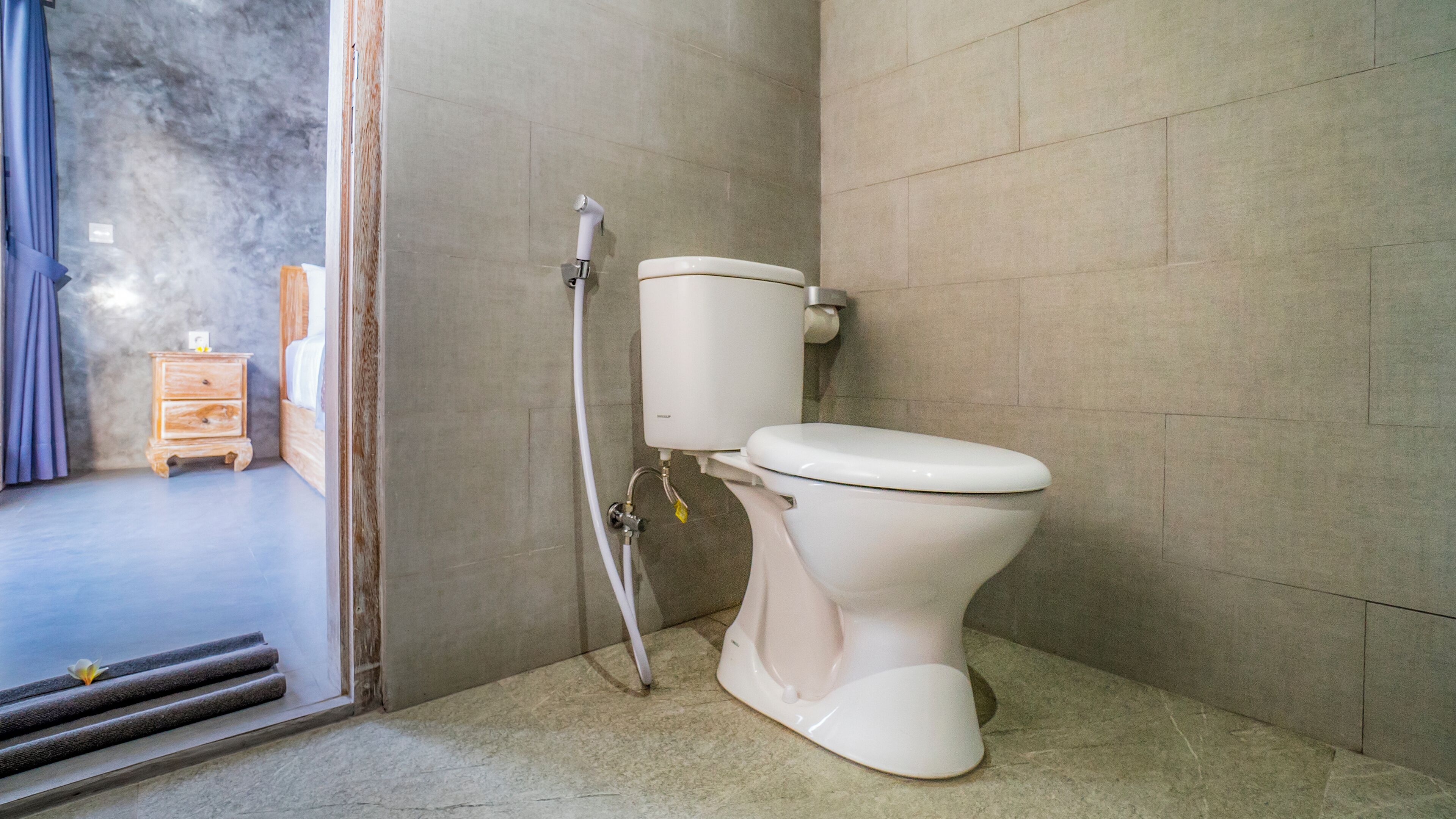 Ein Badezimmer mit Toilette, Dusche und einem kleinen Nachttisch.