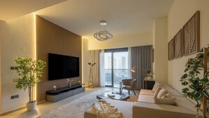 Een moderne woonkamer met een grote flatscreen televisie, een bank, een salontafel en een potplant.