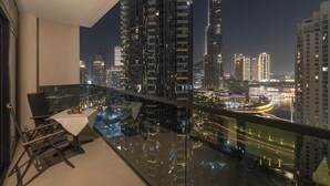 Een balkon met een tafel en stoelen, met uitzicht op een stadsgezicht met hoge gebouwen en een rivier.