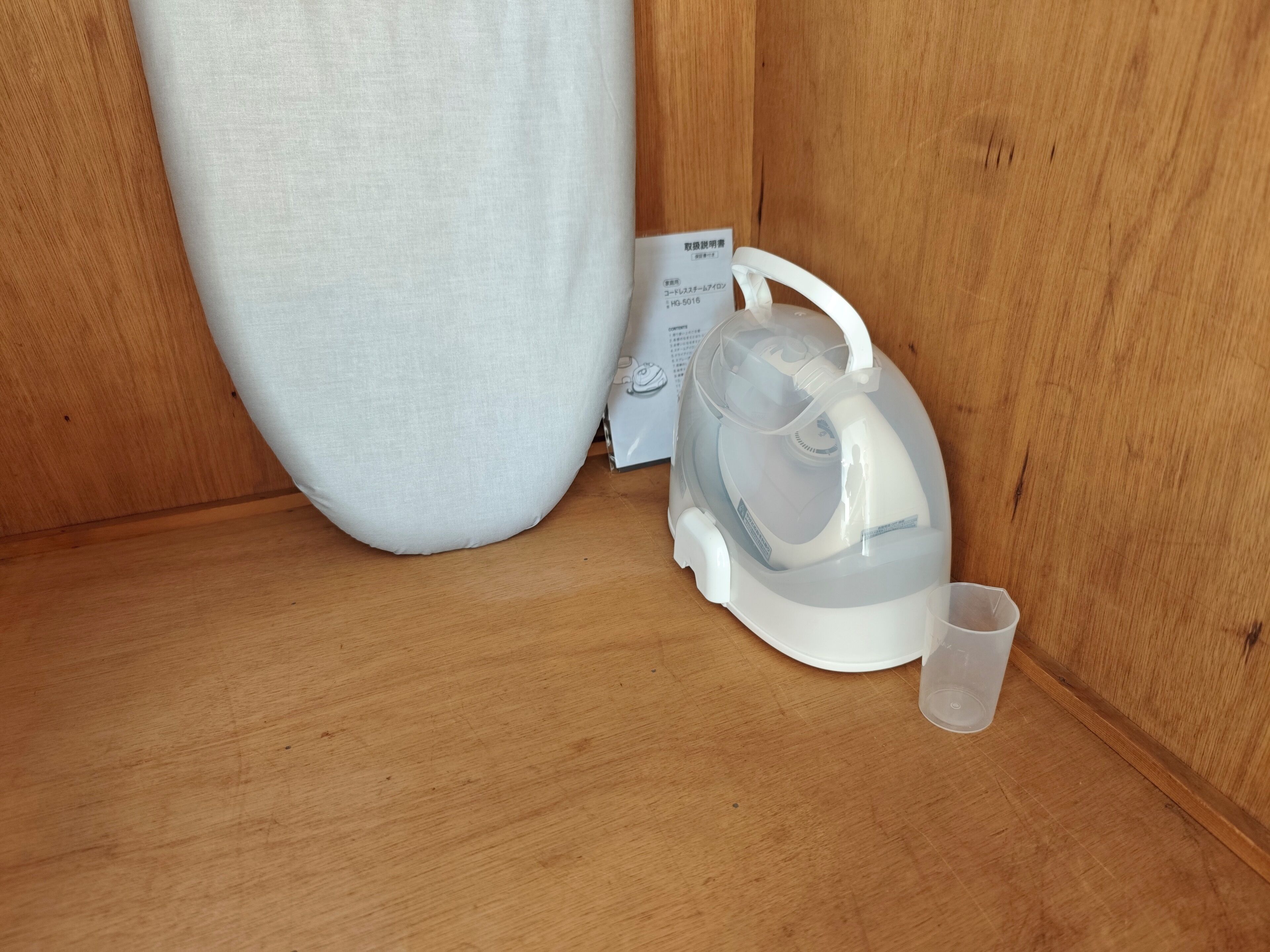 A white kettle with a transparent lid and a small cup on a wooden surface.