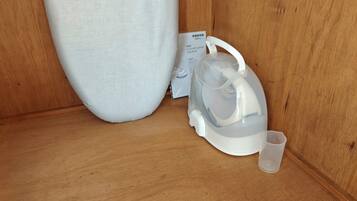 A white kettle with a transparent lid and a small cup on a wooden surface.