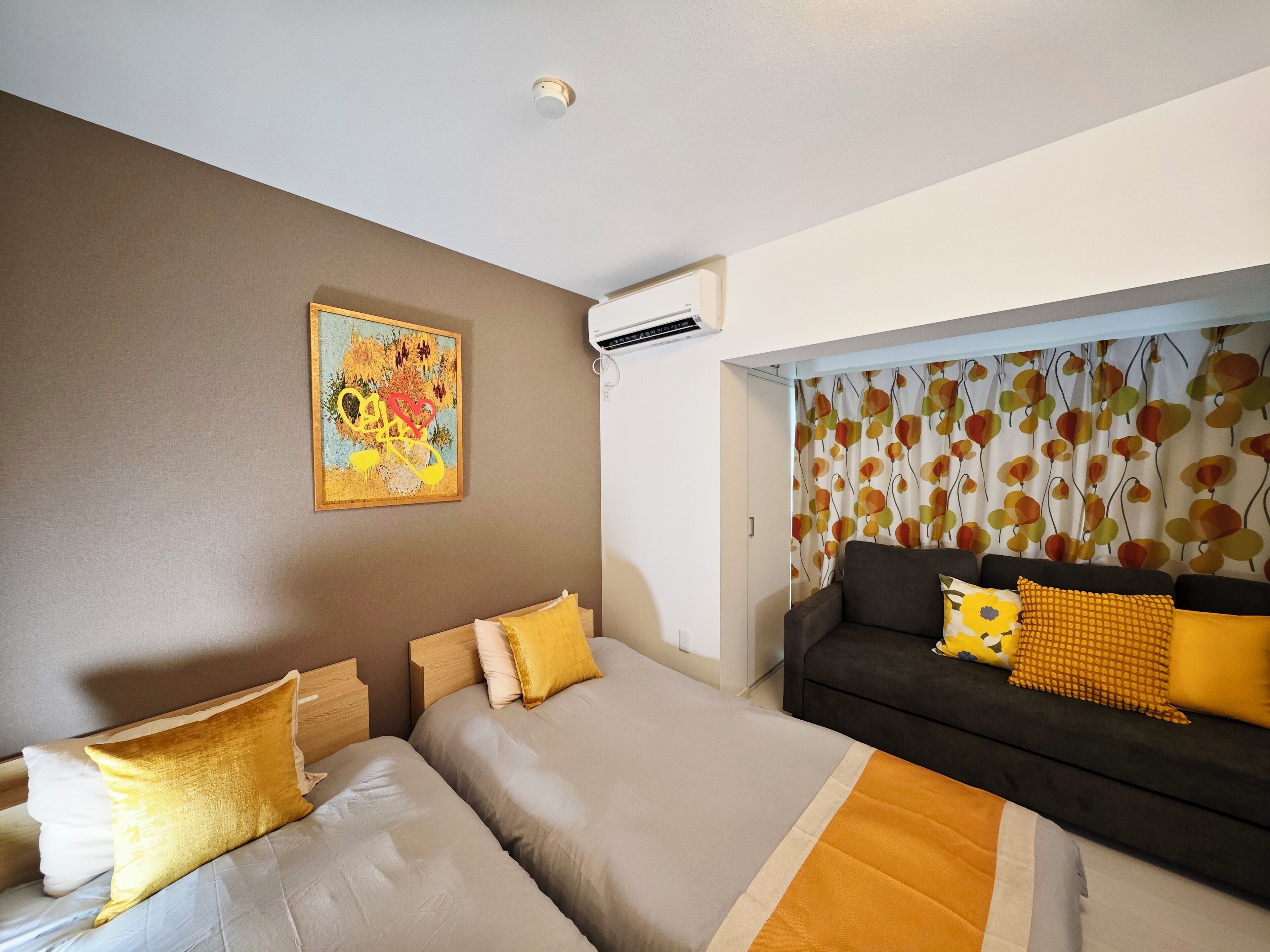 A hotel room with a bed, a sofa, and a painting on the wall.