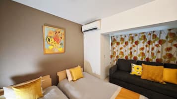A hotel room with a bed, a sofa, and a painting on the wall.