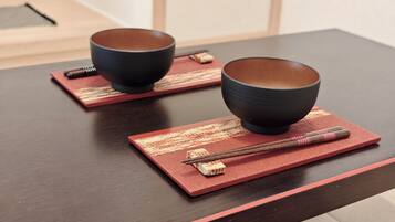 Two bowls on a dark wooden table with chopsticks and a red placemat.