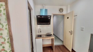 Cocina compacta con lavabo, estufa y campana extractora.