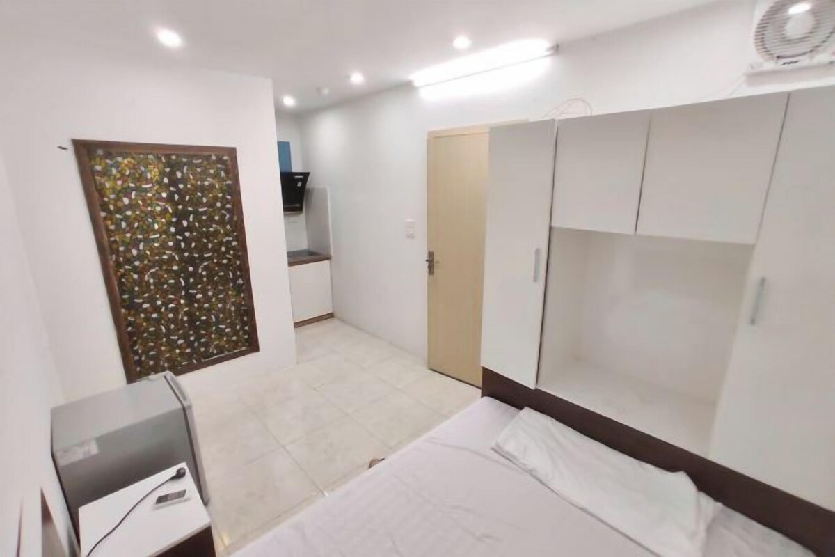 A hotel room with a bed, wardrobe, desk, and a decorative wall panel.