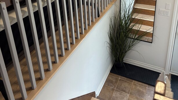 A staircase with white railings and wooden steps, leading to a landing with a mirror reflecting the stairs. - Home away from home (Saint-Philippe)