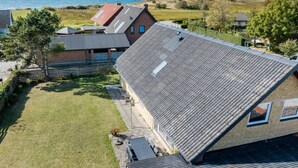 Ein modernes Haus mit geneigtem Dach, einem kleinen Garten und Blick aufs Meer.