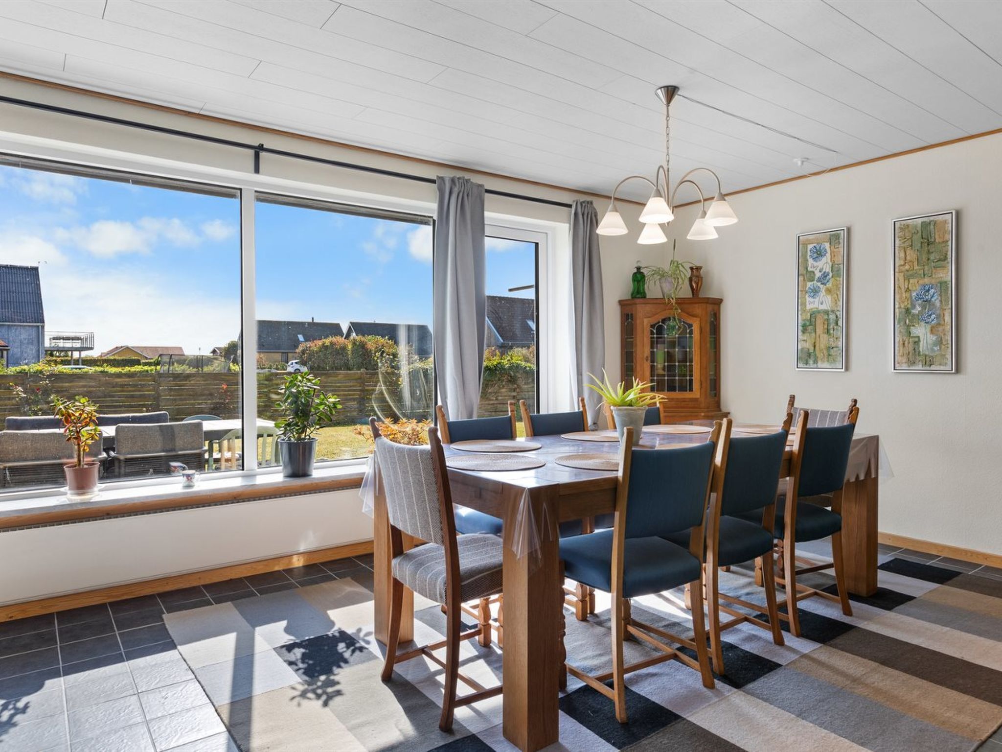 A dining area with a large window, a wooden table, and chairs.