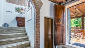 A staircase leading to a wooden door, a small cabinet, and a framed picture on the wall. - Podere Palazzetto by Interhome (Buonconvento)