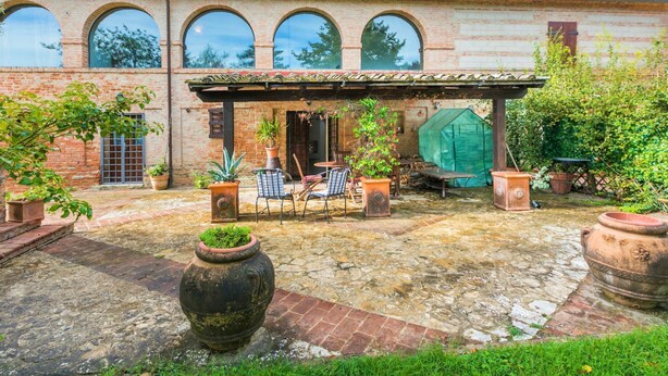 A courtyard with a brick building, outdoor seating, and potted plants. - Podere Palazzetto by Interhome (Buonconvento)
