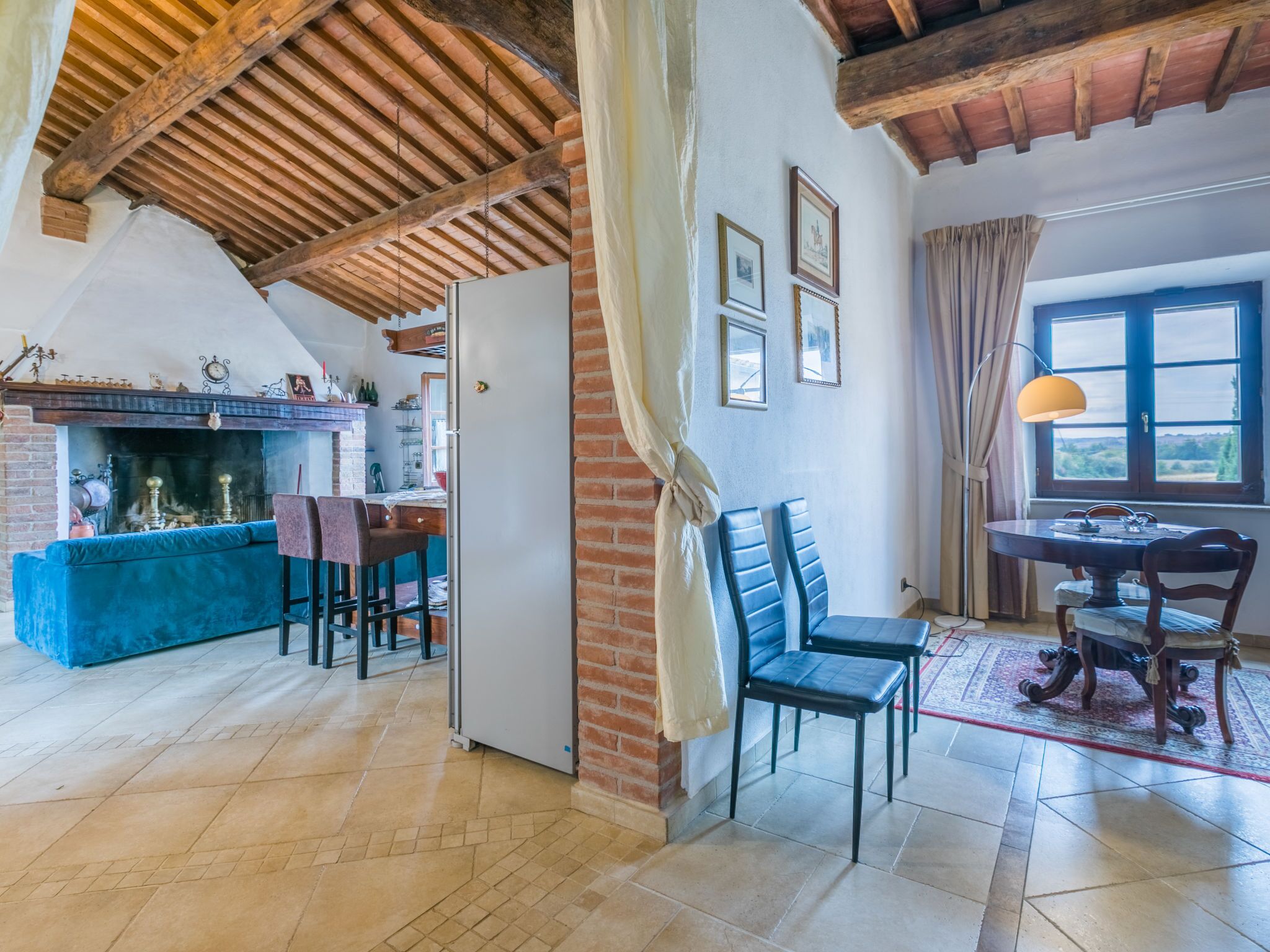Un intérieur rustique avec des poutres apparentes, une cheminée, un coin repas et un espace salon.