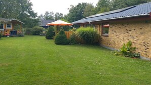 Il s’agit d’une propriété résidentielle dotée d’une pelouse bien entretenue, d’une maison en briques avec un toit en tuiles et d’une clôture en bois.