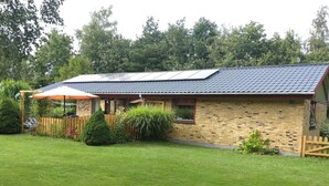 Une maison en briques avec un toit en tuiles et une cour clôturée.