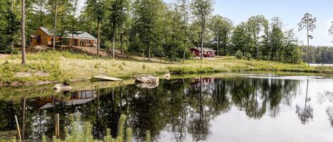 A lakeside cabin with a dock, surrounded by dense forest and a calm lake.