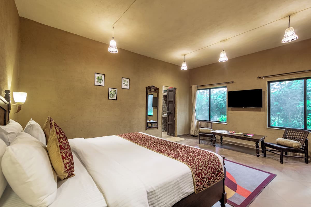 A hotel room with a large bed, a desk, two chairs, and a TV.