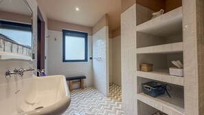 A bathroom with a freestanding bathtub, a shower area, and built-in shelves with storage baskets.