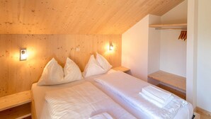 A bedroom with two beds, wooden headboard, bedside lamps, and a wooden shelf. - Inviting chalet on the ski slopes (Sankt Georgen am Kresichberg)