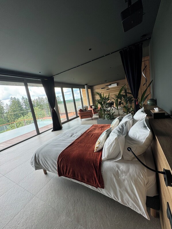 Une chambre moderne avec un grand lit, une tête de lit en bois et une vue sur un balcon.