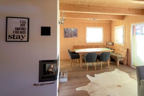 A cozy cabin interior with a fireplace, wooden dining table, and chairs.