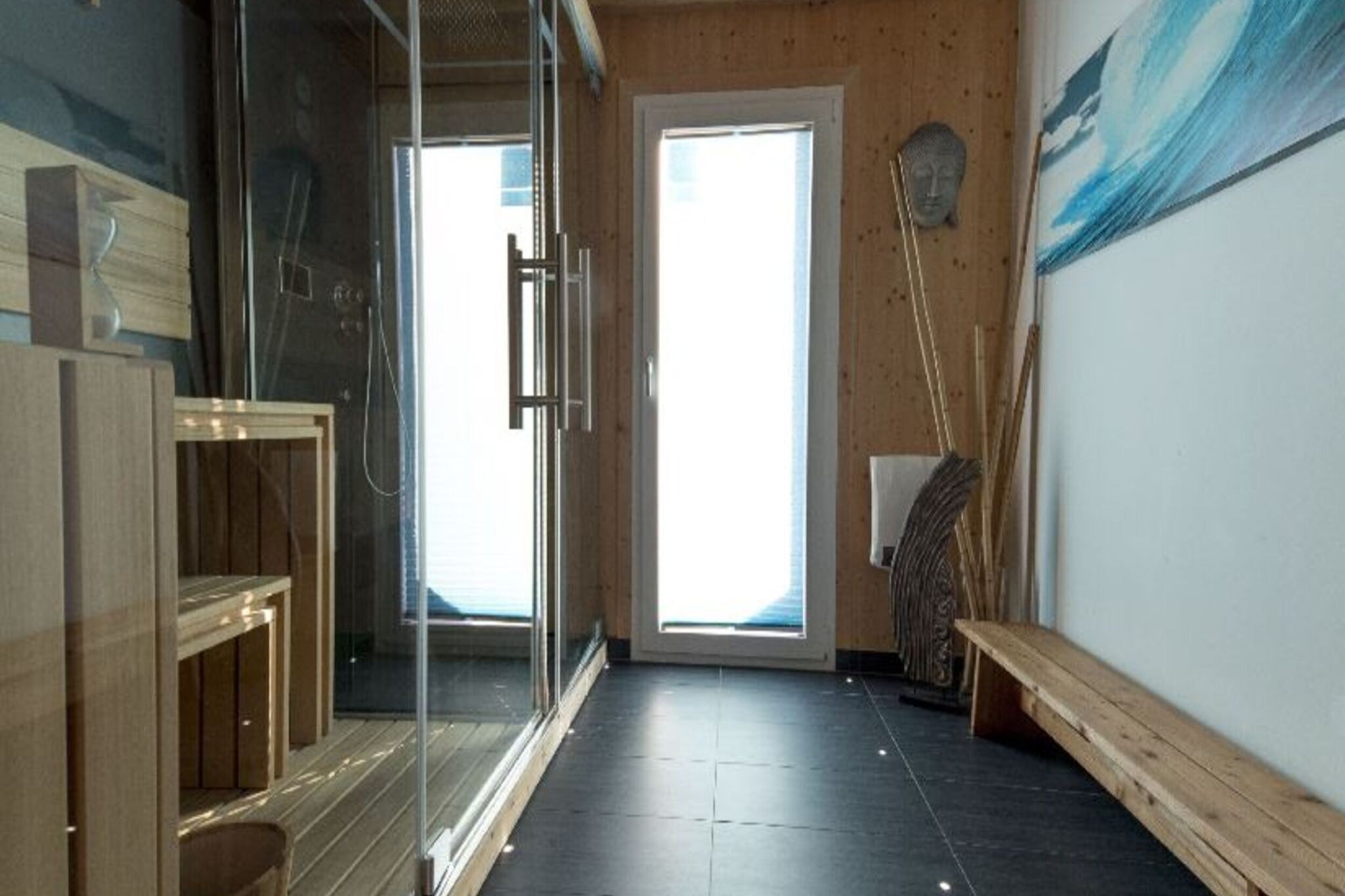 Ein modernes Badezimmer mit Duschkabine aus Glas, einer Holzbank und einem großen Fenster für natürliches Licht.