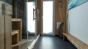 A modern bathroom with a glass shower enclosure, a wooden bench, and a large window providing natural light. - Amazing chalet with sauna (Sankt Georgen am Kresichberg)