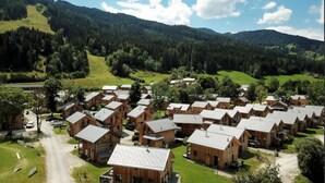 A cluster of wooden cabins with a dirt road in front, surrounded by green hills and a clear sky. - Amazing chalet with sauna (Sankt Georgen am Kresichberg)