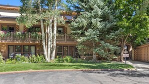 A two-story building with a balcony, surrounded by well-maintained landscaping and trees. - Vail Village Charm - Walk Everywhere (Vail)