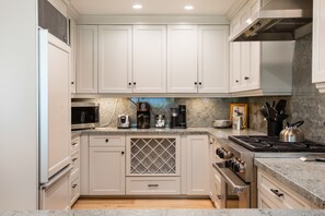 A kitchen with white cabinets, a microwave, a coffee maker, and a gas stove.