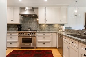 A modern kitchen with white cabinets, a stainless steel stove, and a granite countertop. - EagleVail Home Near Beaver Creek - Hot Tub & Views (Avon)