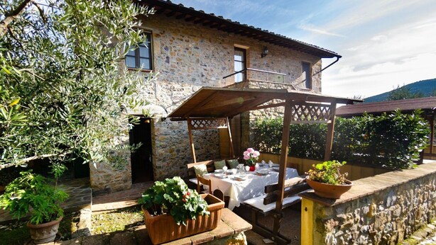 Un bâtiment en pierre doté d’un patio couvert, d’un espace extérieur aménagé pour s’asseoir et de plantes en pot.