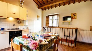 Une cuisine chaleureuse avec une table à manger pour deux personnes, un poêle et une fenêtre donnant sur un beau paysage.