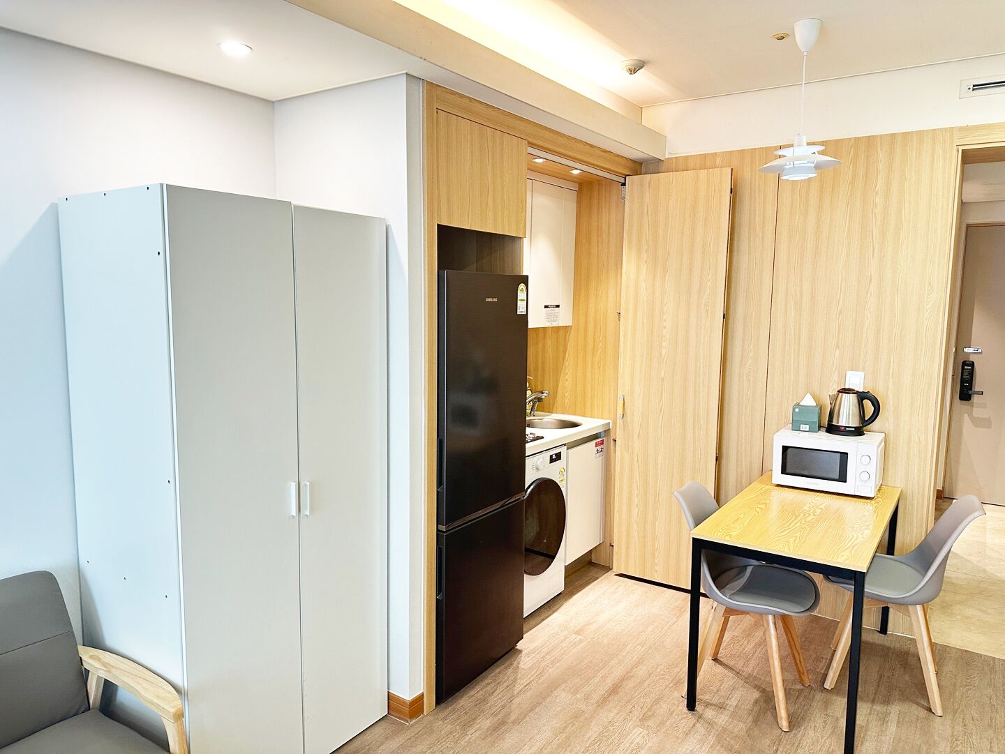 A compact kitchen with a microwave, sink, and a small table with chairs.