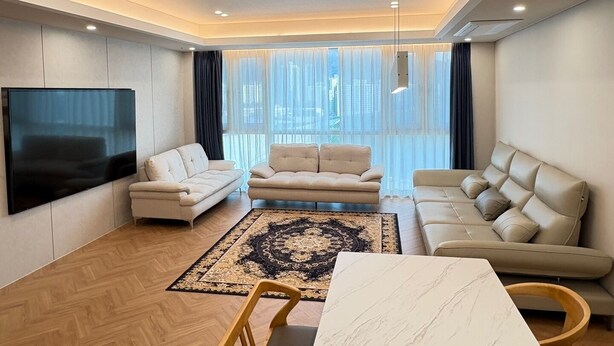 A modern living room with a flat-screen TV, two sofas, a coffee table, and a patterned rug. - CENTUMCITY HOTEL (Busan)